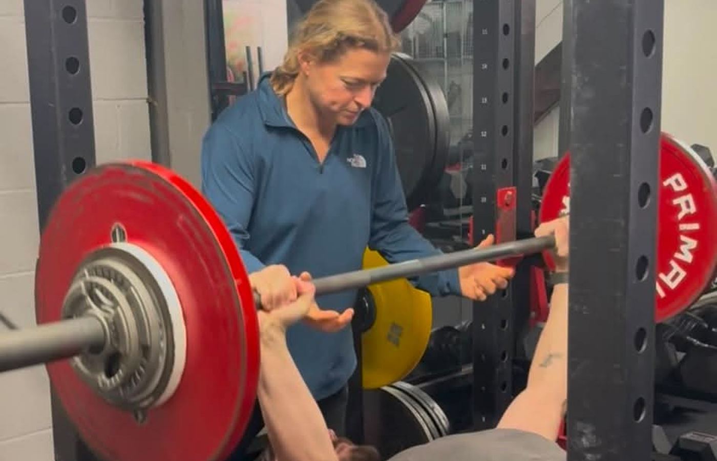 A coach spotting a member through a bench press at Amazon24 Fitness